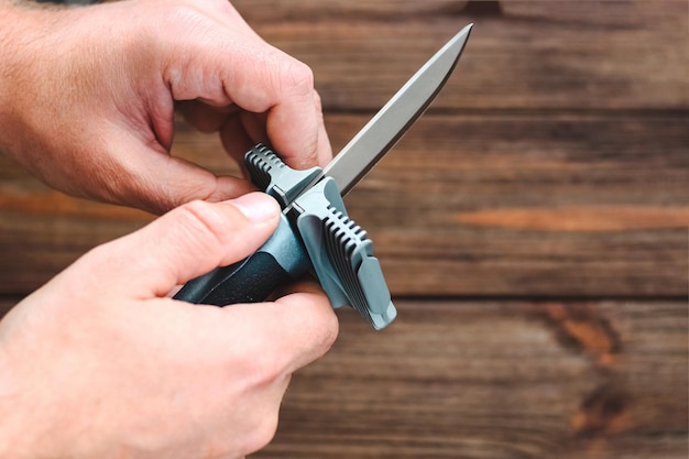 Photo hands sharpening a knife on a wooden background