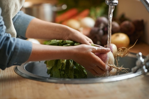 Hands sink and water to clean vegetables in kitchen health and hygiene with chef cooking food and closeup Turnip nutrition and organic for meal vegan or vegetarian with person washing produce