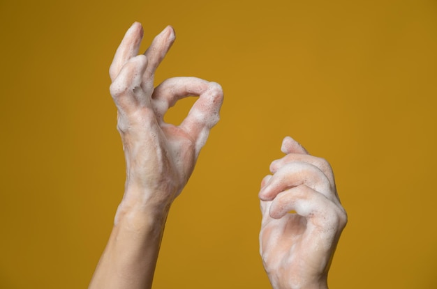 Hands in soapy foam one of them shows a ok sign with her fingers