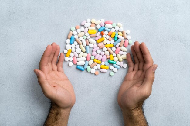 Photo hands surrounding colorful pills on light background