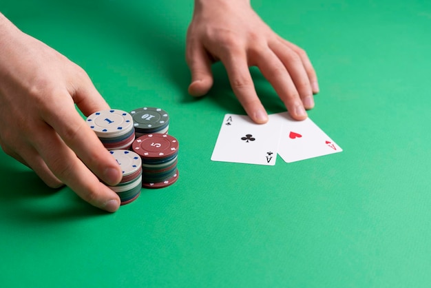 The hands take the casino poker chips on the green table, gambling and luck concept