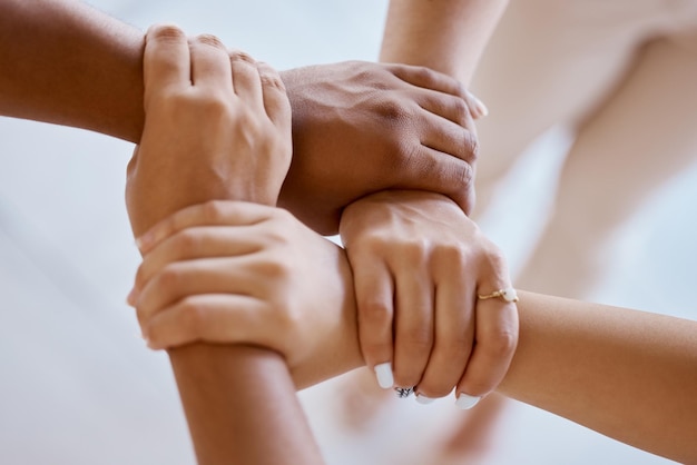 Hands together and solidarity with a group of people strong in unity from above for teamwork or collaboration Trust support and community with a team or partnership holding a wrist for motivation