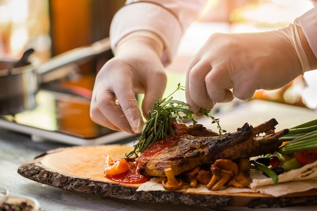 Hands touch green herbs. Cooked meat and mushrooms. Grilled pork with fragrant rosemary. High-calorie lunch.