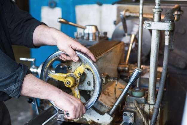 The hands of the turner rotate the wheel of the quill of the lathe