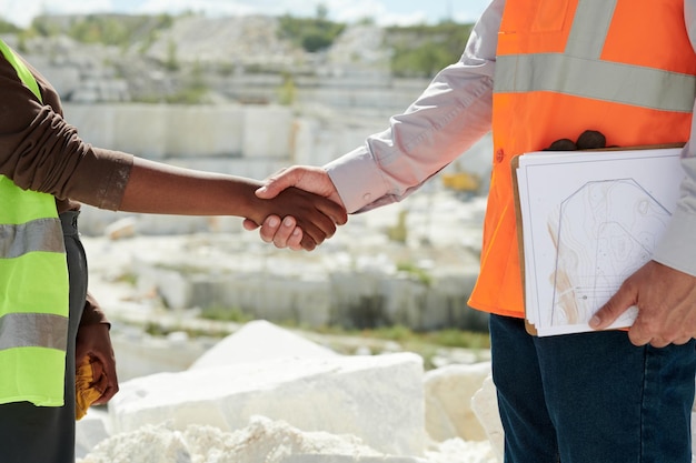 Hands of two young interracial workers of marble quarry greeting each other