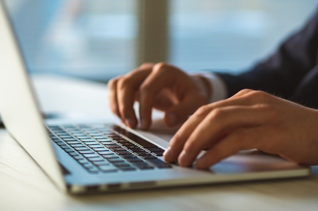 The hands typing on the laptop keyboard