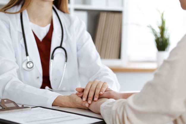 Hands of unknown woman-doctor reassuring her female patient, close-up. Medicine concept.