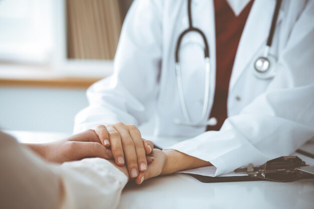 Hands of unknown woman-doctor reassuring her female patient, close-up. Medicine concept.