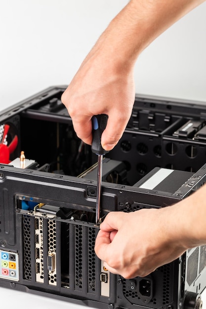 Hands unscrewing a video card bracket while maintenance personal computer hardware with selective focus