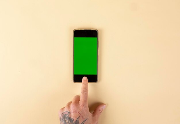 hands using mobile phone with green screen isolated on a pastel colored background