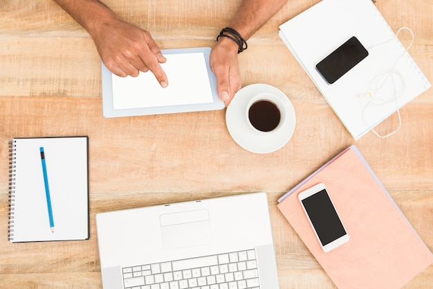 Hands using tablet next to several devices