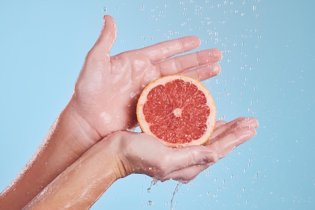 Hands water splash and grapefruit cosmetic skincare for vitamin c nutrition citrus health treatment and natural wellness with hygiene Aesthetic advertising hydration and a blue studio background