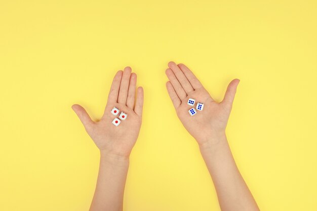 Hands with dice on a yellow background.