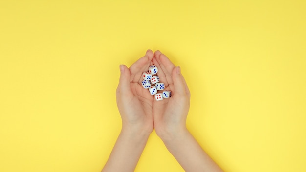 Hands with dice on a yellow background.