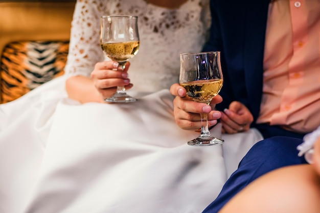 Hands with glasses of champagne bride and groom at wedding