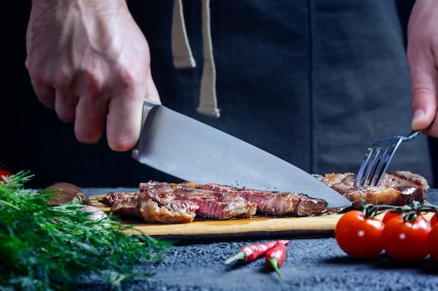 hands with knife and fork cutting a cooked steak