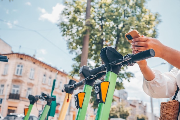 Hands with a phone on the background of an electric scooter an application for the use of transport