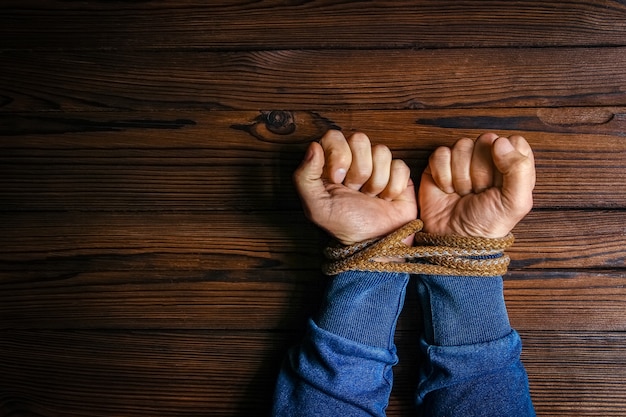 Hands with a rope on a wooden background