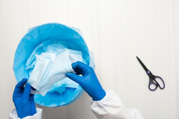 Hands with scissors cut through the medical mask.