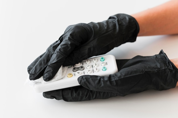 Hands with surgical gloves disinfecting remote control