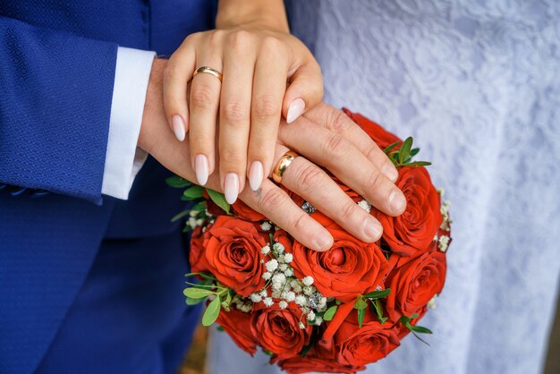 Photo hands with wedding rings on the bride's bouquet