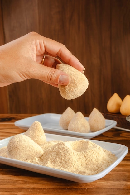 Hands of woman breading brazilian croquette 