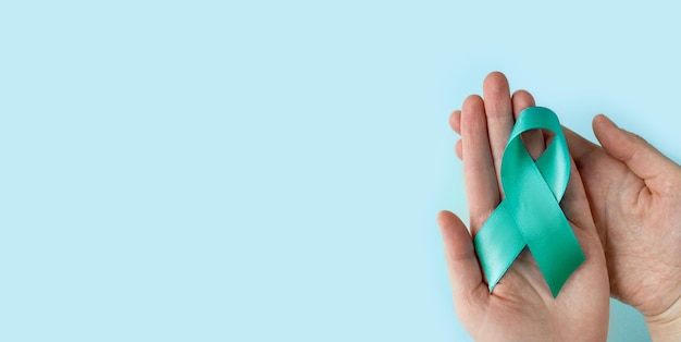 Hands of woman holding Teal ribbon Symbolic for cervical cancer ovarian cancer gynecological cancer