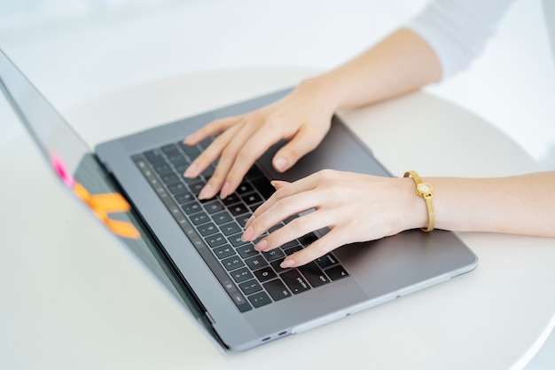 Hands of a woman operating a laptop in a bright room