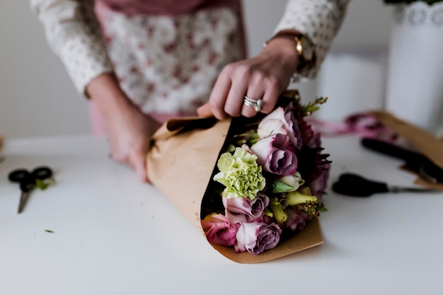 Hands of woman wrapping bunch to paper