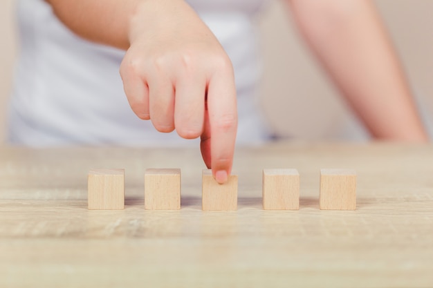 Hands of women,stacking wooden blocks into steps.