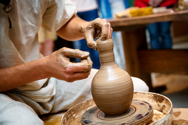 Hands working on pottery wheel, making a vase