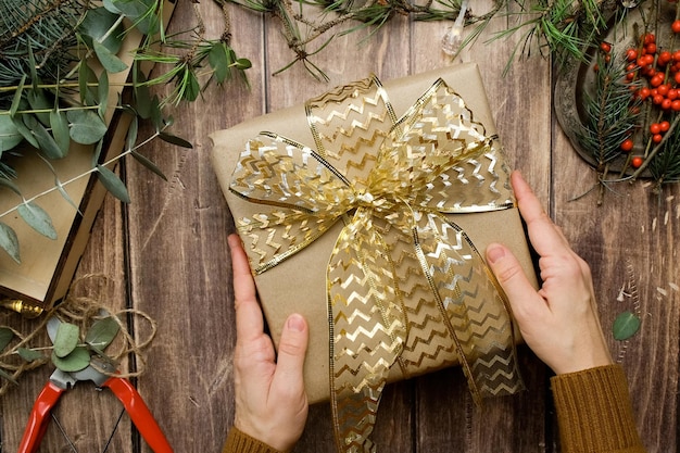 Hands wrapping Christmas present decorating with ribbon bow