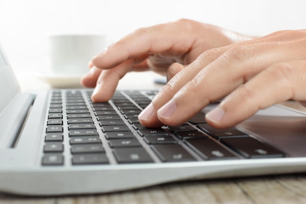 Hands writing on a laptop keyboard in the office in closeup