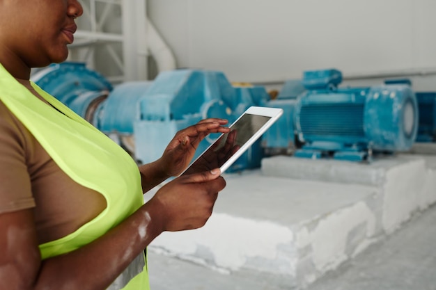 Hands of young african american female worker of factory using tablet