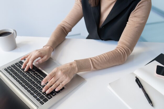 Hands of young businesswoman over laptop keypad during work over new business project in office