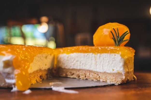 Hands of young chef baker cutting slice of mango cheesecake