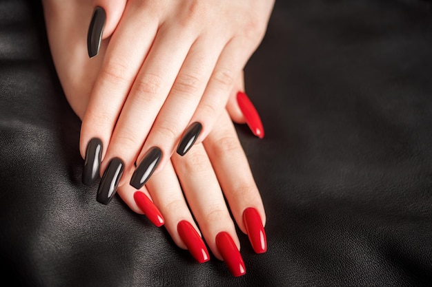 Hands of a young girl with black and red manicure on nails