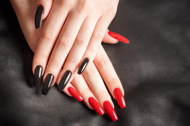 Hands of a young girl with black and red manicure on nails