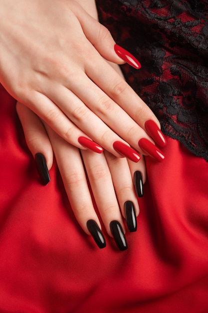 Hands of a young girl with black and red manicure on nails