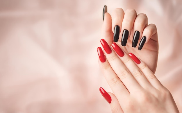 Hands of a young girl with red and black manicure on nails