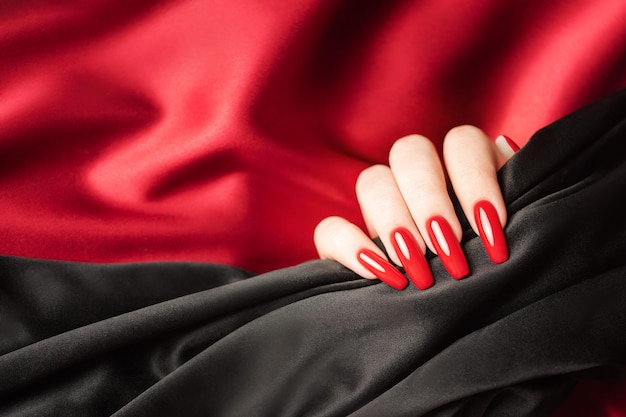 Hands of a young girl with red and black manicure on nails