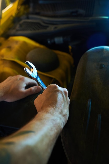 Hands of young muscular technician or repairman with metallic wrench