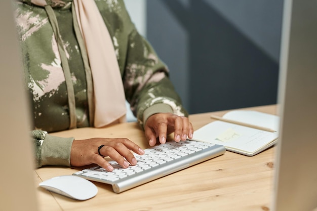 Hands of young muslim businesswoman in casualwear typing on computer keyboard while developing new s