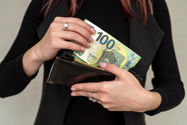 Hands of a young stylish luxury woman with beautiful eyes holding a wallet in which the euro to pay Business concept