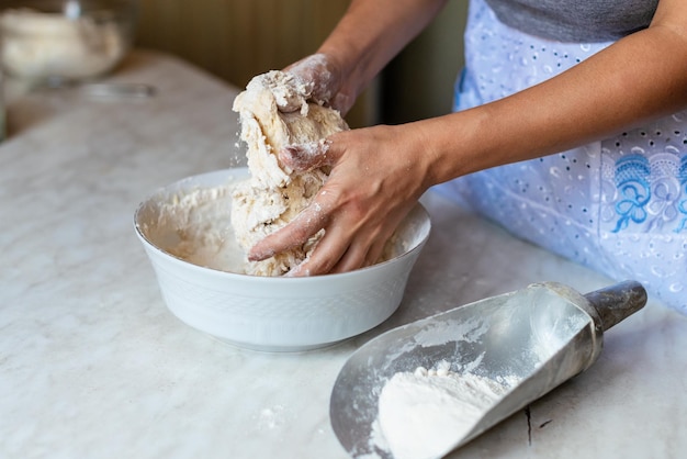 Hands of a young woman kneading dough to make bread or pizza at home Production of flour products Making dough by female hands