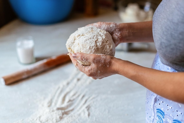 Hands of a young woman kneading dough to make bread or pizza at home Production of flour products Making dough by female hands