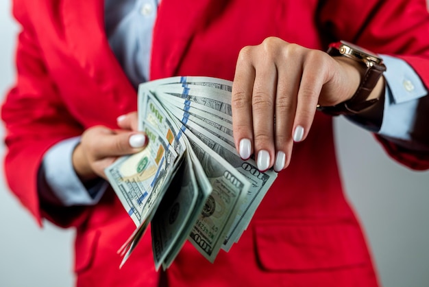 Hands of young woman in red clothes with dollars them standing isolated on white background