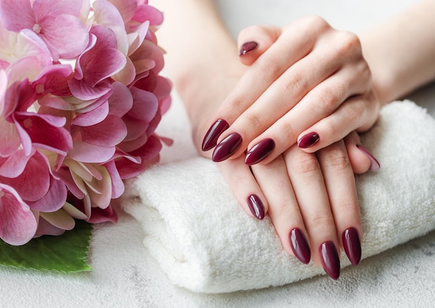 Photo hands of a young woman with dark red manicure on nails