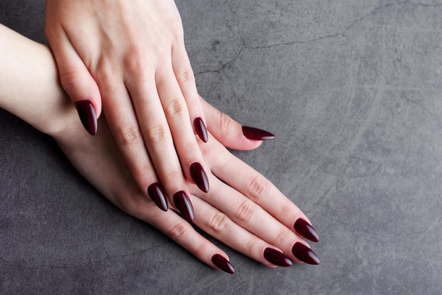 Hands of a young woman with dark red manicure on nails