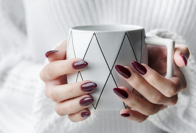 Hands of a young woman with white manicure on nails